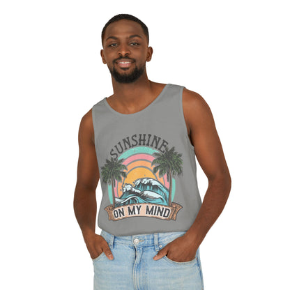 A man wearing a gray tank top with a graphic design and text, smiling at the camera.