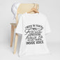 A white t-shirt with black text printed on it, hanging on a wooden chair.