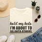 a casual outfit laid out on a flat surface, including a white t-shirt with a humorous text, sunglasses, a hat, and some potted plants.