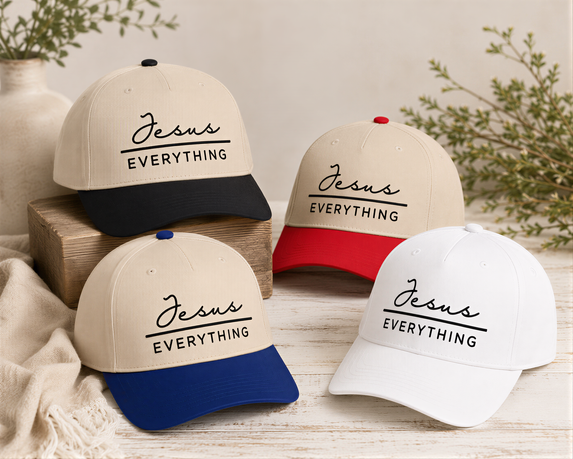 four baseball caps with the text "Jesus Everything" printed on them, arranged on a wooden surface.