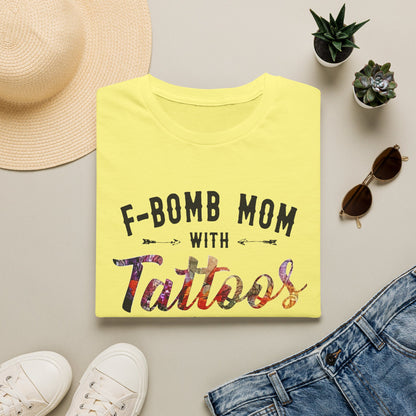 a yellow t-shirt with the text "F-BOMB MOM WITH TATToos" printed on it, along with a pair of sunglasses, a hat, and some plants.