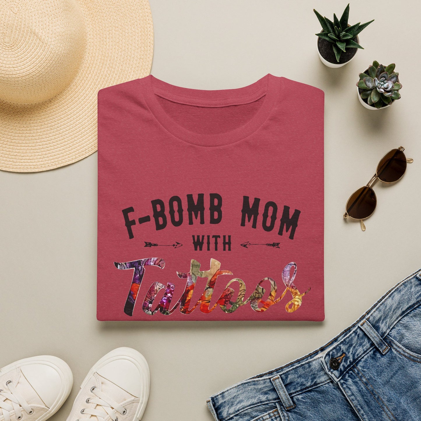 a red t-shirt with the text "F-BOMB MOM WITH Tattoo" printed on it, along with a pair of jeans, sunglasses, and a straw hat.