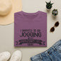 a purple t-shirt with a humorous text, a pair of jeans, sunglasses, a hat, and some potted plants arranged on a flat surface.
