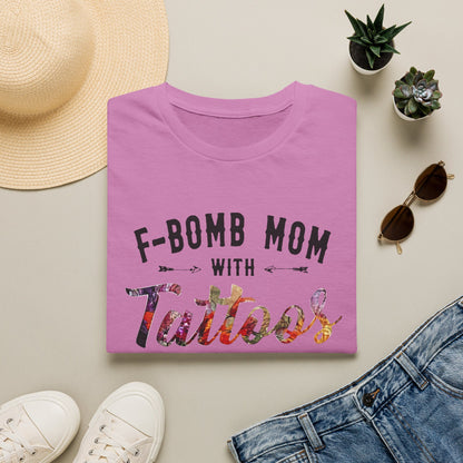 a pink t-shirt with the text "F-BOMB MOM WITH Tattoos" printed on it, along with a pair of jeans, sunglasses, and a straw hat.