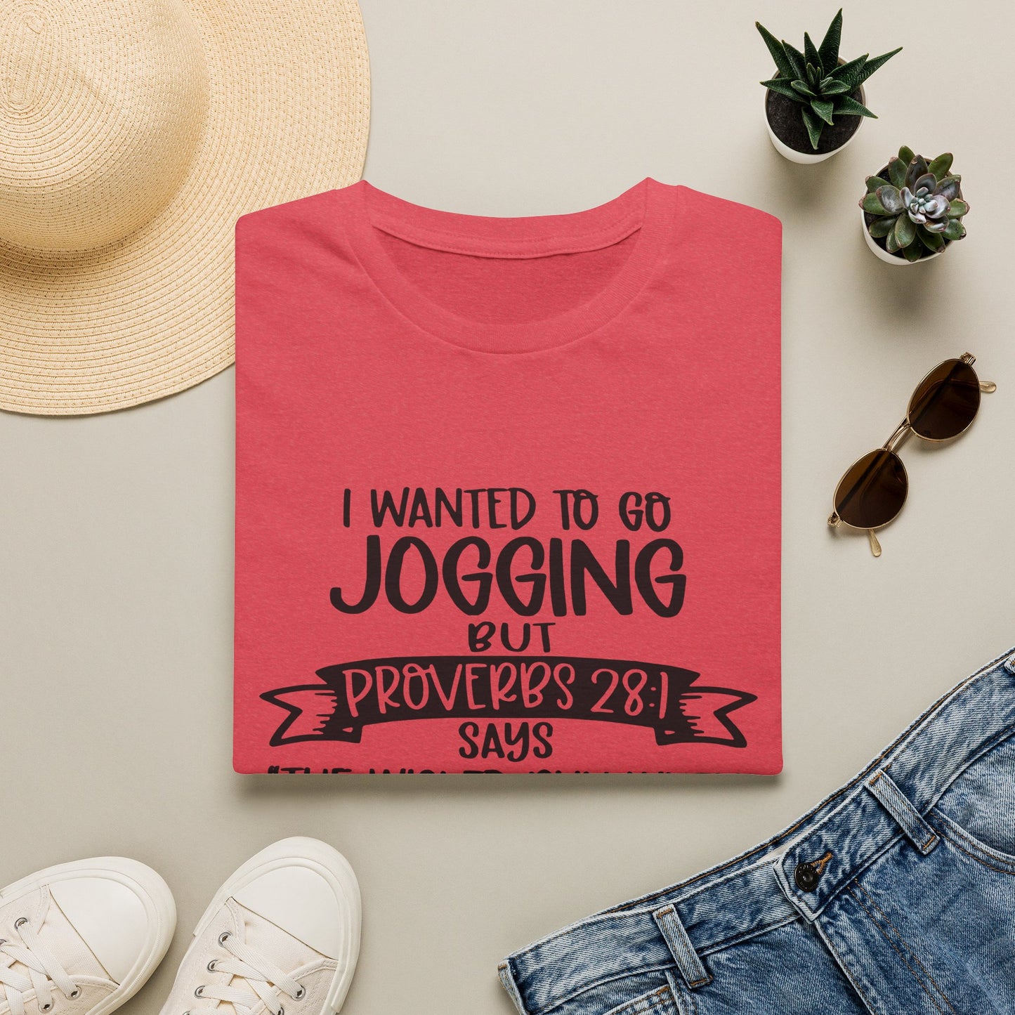 a red t-shirt with a humorous text, a pair of jeans, sunglasses, a hat, and some potted plants arranged on a light-colored surface.