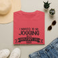 a red t-shirt with a humorous text, a pair of jeans, sunglasses, a hat, and some potted plants arranged on a light-colored surface.