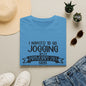 a blue t-shirt with a humorous text, a pair of jeans, sunglasses, a hat, and some potted plants arranged on a flat surface.