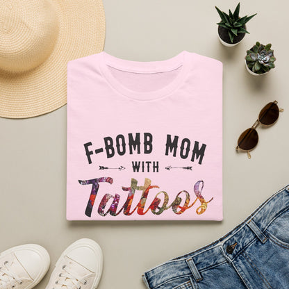 a pink t-shirt with the text "F-BOMB MOM WITH TATToos" printed on it, along with a pair of jeans, sunglasses, and a straw hat.