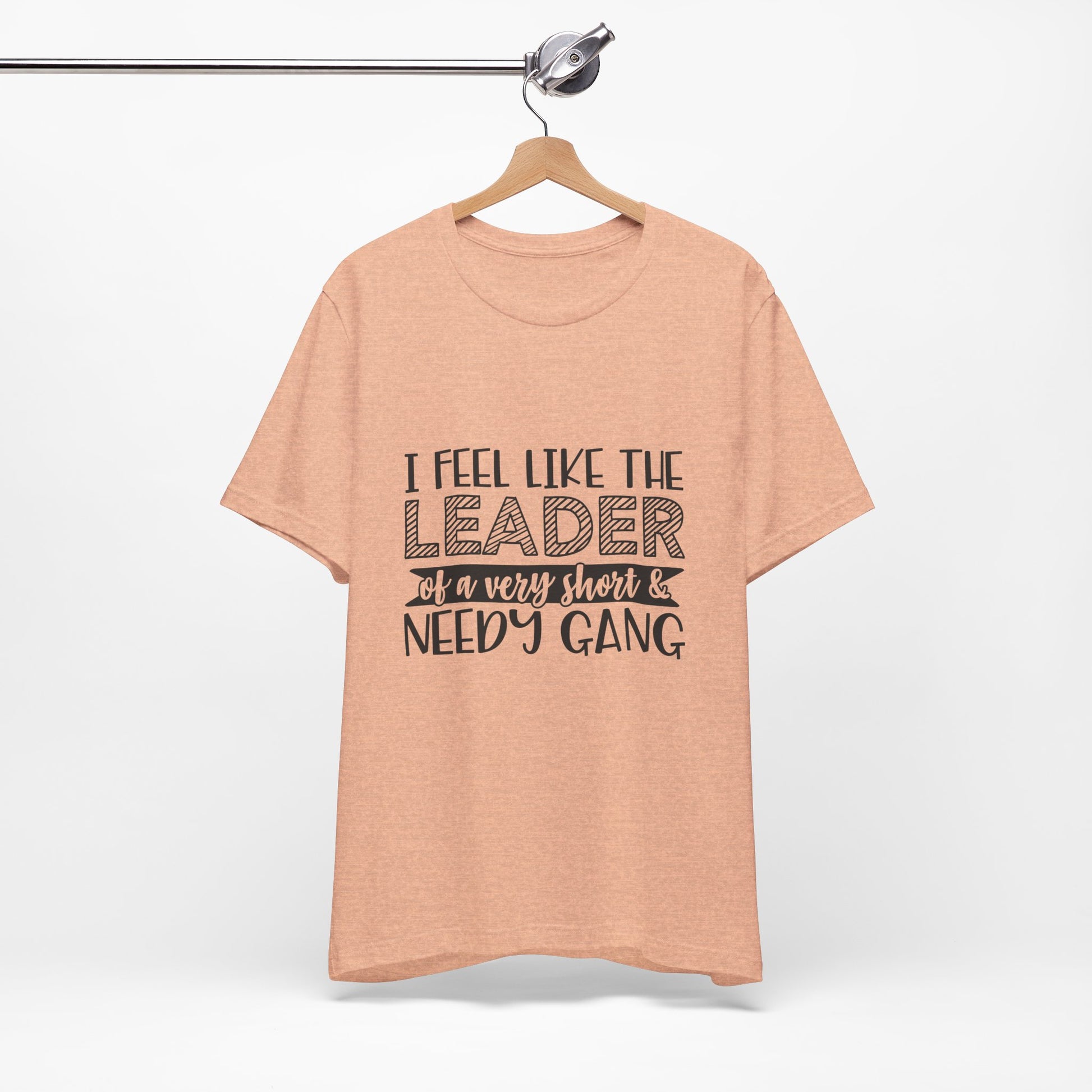 A peach-colored t-shirt with the text "I feel like the leader of a very short & NEEDY GANG" printed on it.