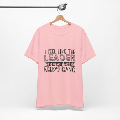 A pink t-shirt with text printed on it, hanging on a wooden hanger.