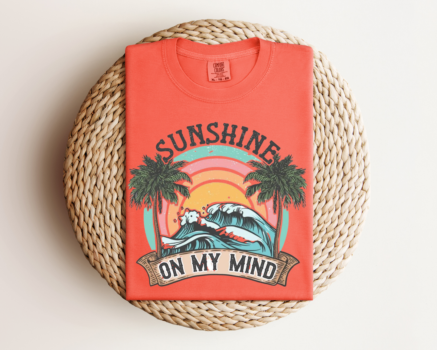 a red t-shirt with a graphic design depicting a sunset and palm trees, along with the text "SUNSHINE ON MY MIND".