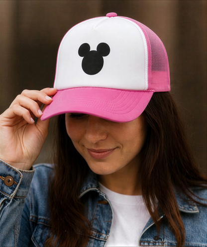 A woman wearing a pink and white baseball cap with a Mickey Mouse logo on it.